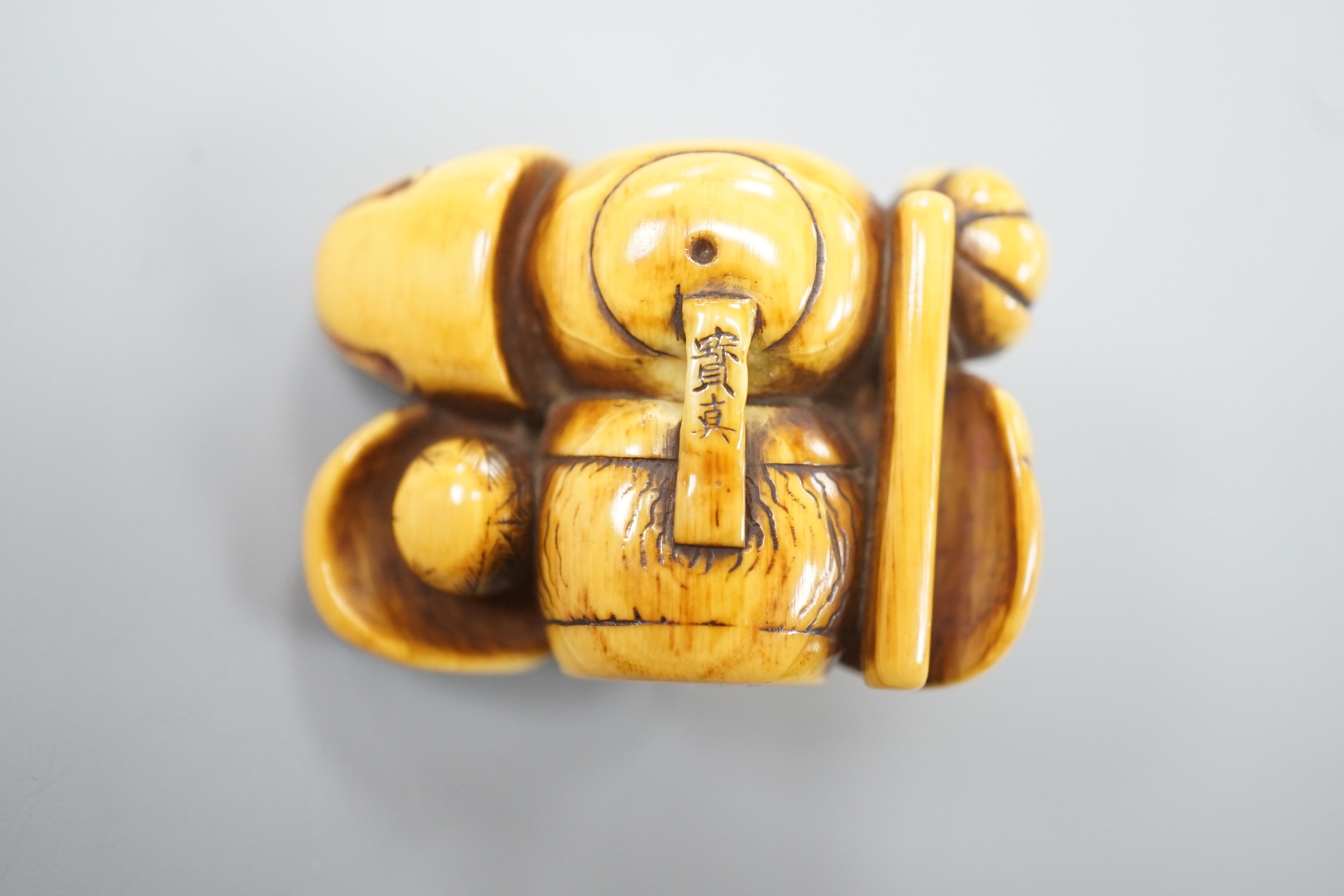 A Japanese ivory netsuke of a Daruma doll and four noh masks, signed, 19th century, 3.8cm